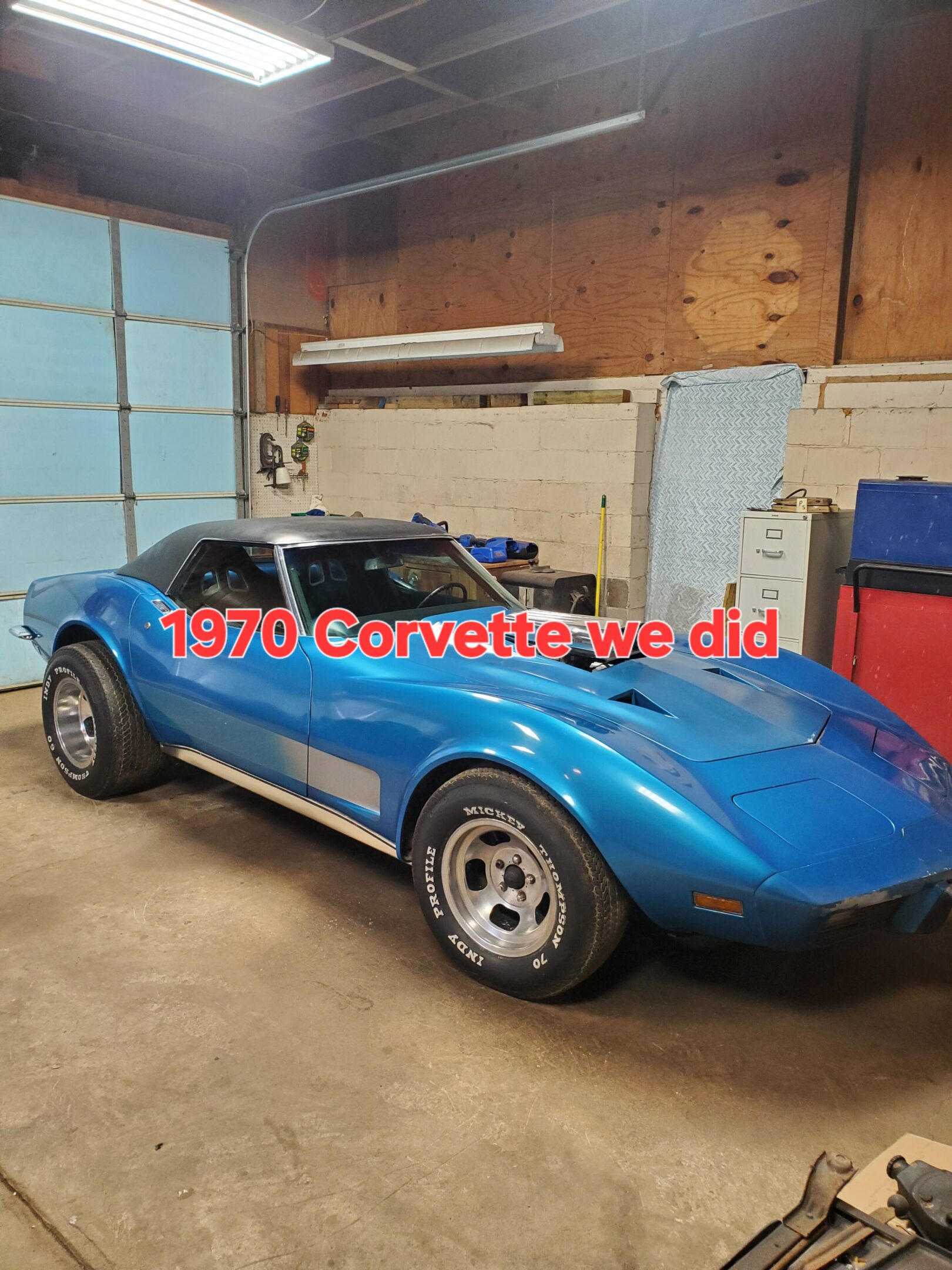 A blue corvette is parked in the garage.